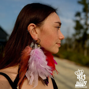 Woman wearing feather earrings with a blurred outdoor background